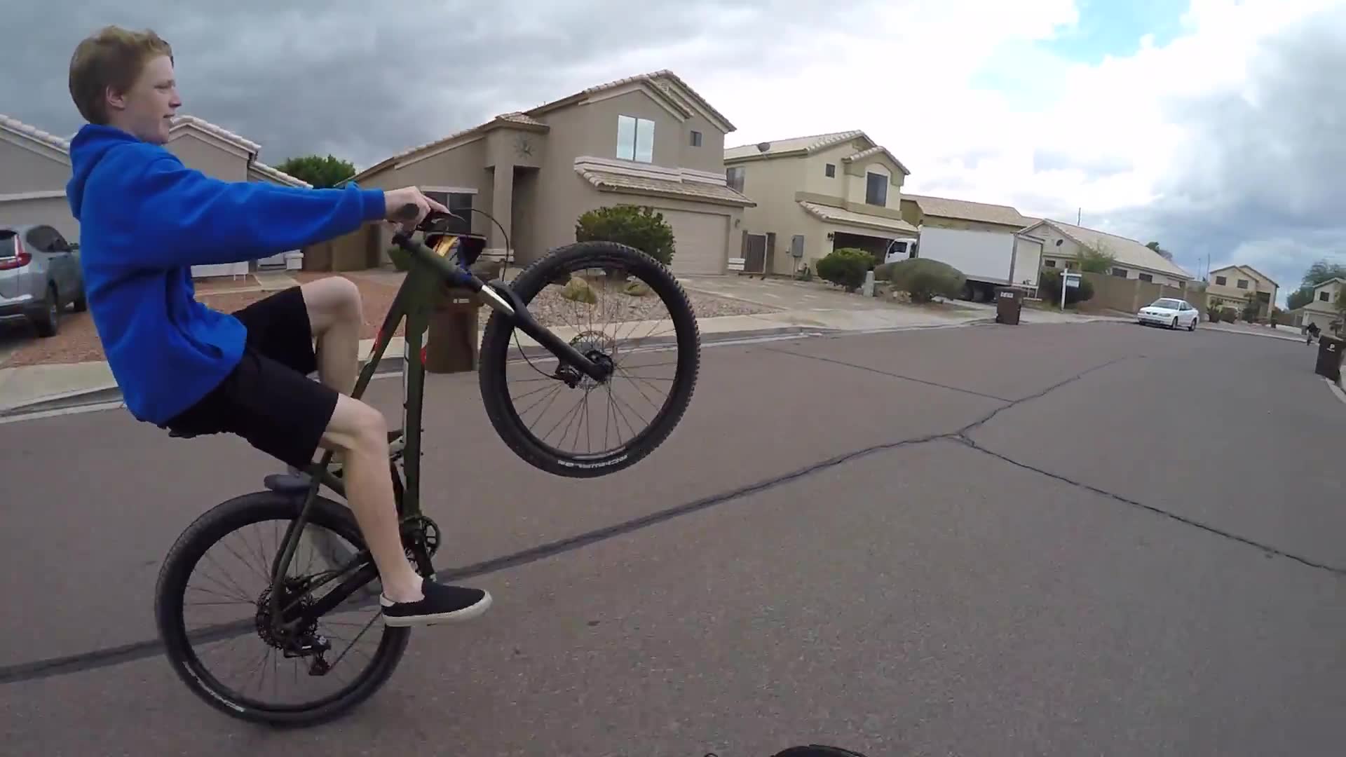 Young children demonstrate impressive bicycle wheelie skills to motorcyclists