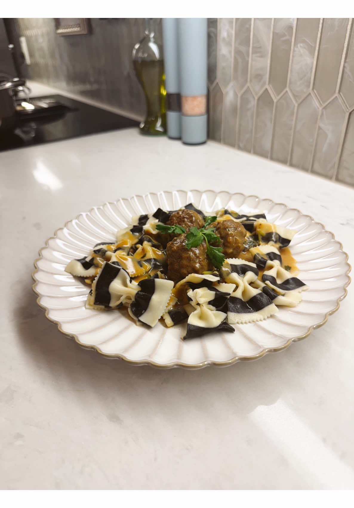 Making striking black and white farfalle pasta with juicy meatballs and savory sauce