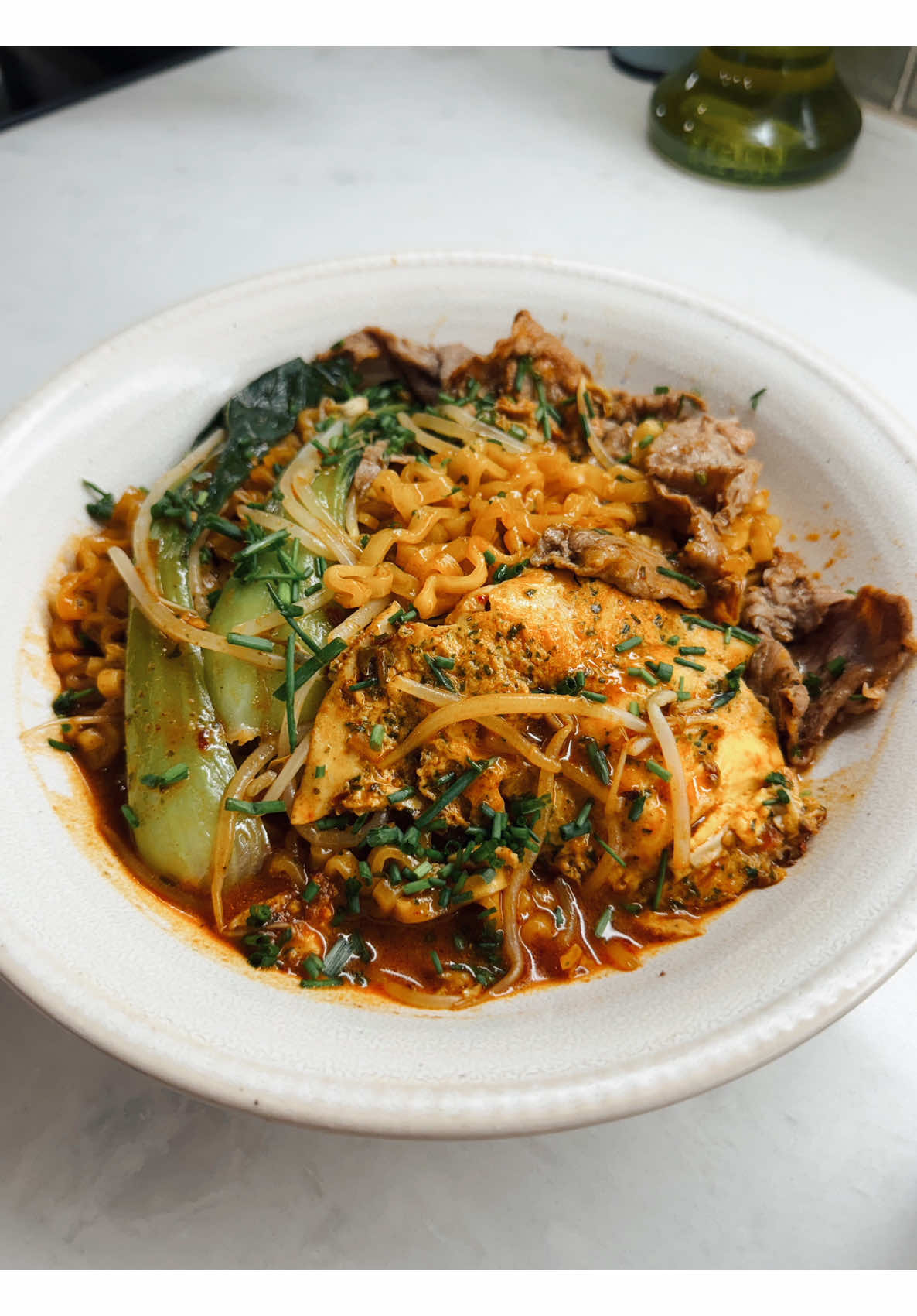 Making a spicy beef ramen bowl loaded with bok choy, bean sprouts, and a fried egg