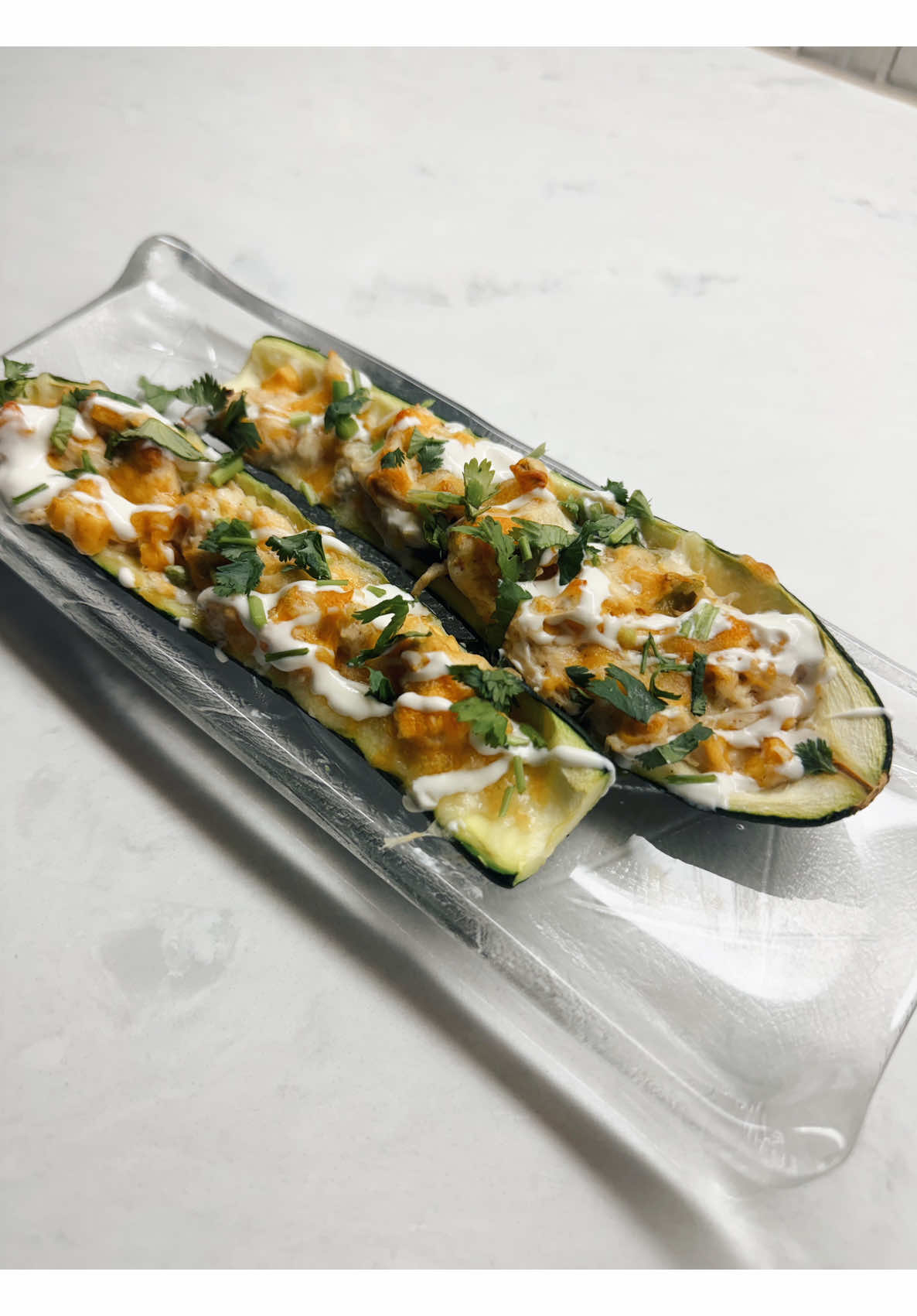 Making spicy buffalo chicken zucchini boats topped with creamy sauce and cilantro